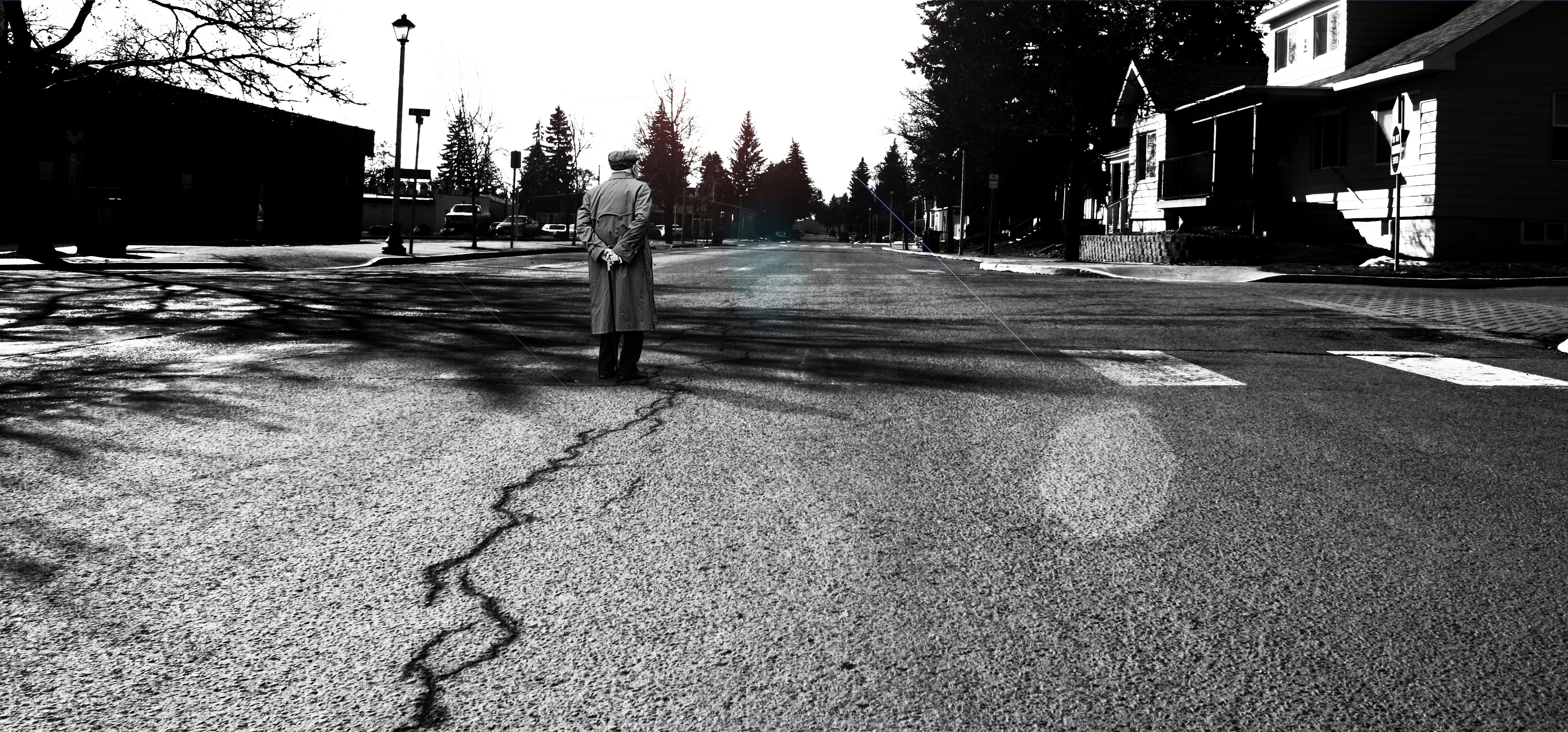 man standing in the middle of the road grayscale photography